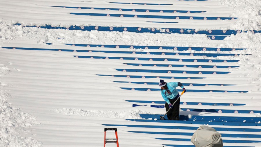 A stadium worker clears snow from seats before an NFL wild-card playoff football game between the Buffalo Bills and the Pittsburgh Steelers, Monday, Jan. 15, 2024